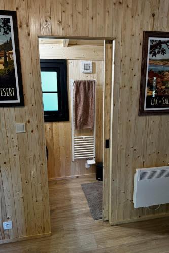 Cette chambre est dotée de murs en bois et d'une porte avec fenêtre. dans l'établissement Evasion en cabane en bois proche du lac du Salagou entourée de nature, à Clermont-lʼHérault