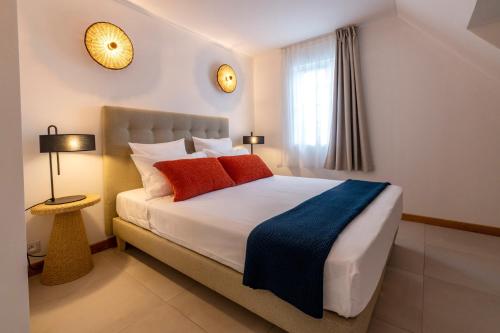 a bedroom with a bed with red and blue pillows at Maison de Vacances Tiffany Blue in Grand Baie