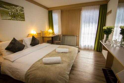 een hotelkamer met een groot bed met 2 kussens bij Hotel Bristol in Saas-Fee