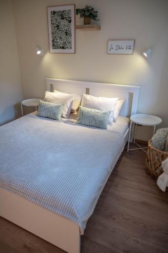a large bed with blue and white sheets and pillows at One24 House in Čortanovci