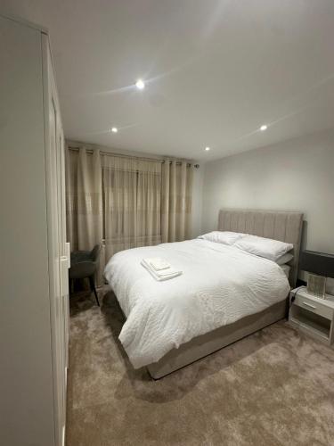 a bedroom with a large white bed and a chair at Modern Room in Cheshunt in Cheshunt