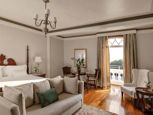 a bedroom with a bed and a couch and a table at Hotel das Cataratas, A Belmond Hotel, Iguassu Falls in Foz do Iguaçu