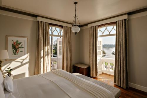 a bedroom with a large bed and large windows at Hotel das Cataratas, A Belmond Hotel, Iguassu Falls in Foz do Iguaçu