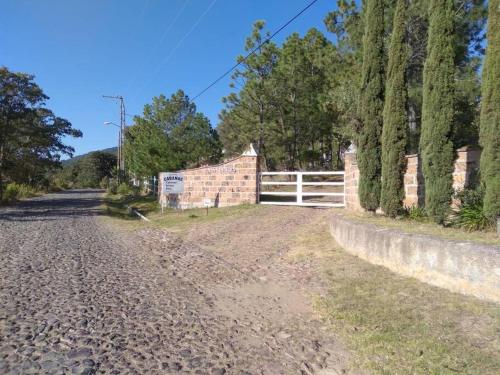 a dirt road with a white fence and trees at Cabaña Amealco Pino in Amealco