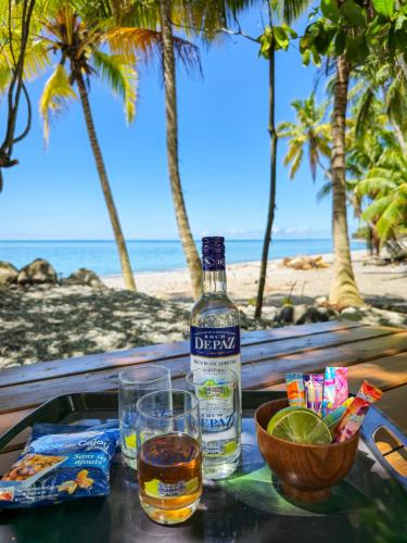 a bottle of whiskey and glasses on a table on the beach at Ti Kay Paradi T3 - Les pieds dans l'eau in Saint-Pierre