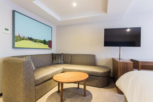 a hotel room with a couch and a bed and a tv at Cottons Hotel and Spa in Knutsford