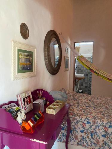 una camera da letto con un letto viola e uno specchio di casa arandu a Amontada