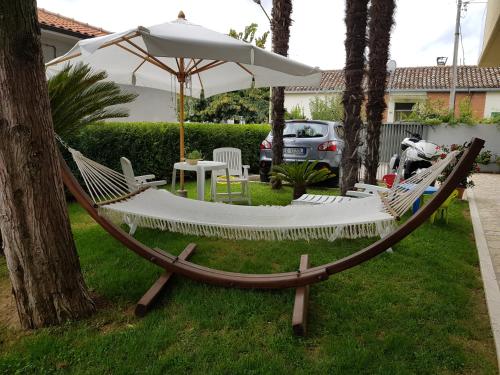 a hammock with an umbrella in a yard at B&B LA CASA DEL CASALE in Roseto degli Abruzzi