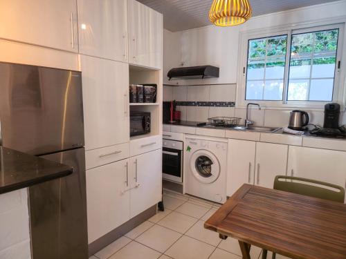 a kitchen with white cabinets and a table and a sink at Villa Ti Kay Paradi - Accès plage direct in Saint-Pierre