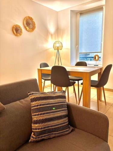 un salon avec un canapé et une table avec des chaises dans l'établissement Le Chalet Urbain - Montélimar, à Montélimar