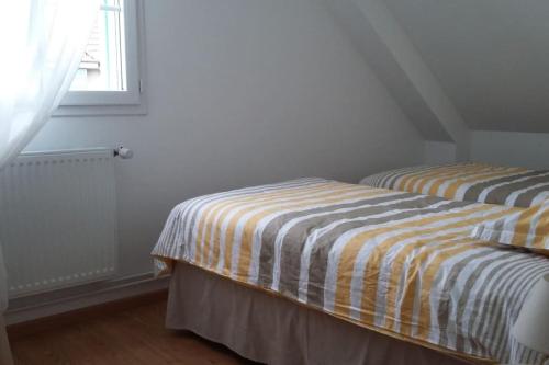 deux lits jumeaux dans une chambre avec fenêtre dans l'établissement Maison, gîte en Baie de Somme à Saint-Valery-sur-Somme, à Saint-Valery-sur-Somme