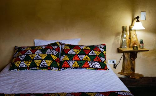 a bed with a colorful pillow and a lamp at Luna Verde Eco Hábitat in Rionegro