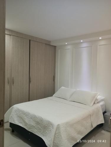 ein Schlafzimmer mit einem weißen Bett und Holzschränken in der Unterkunft Upar Suite Apartamento con Aire Acondicionado y piscina in Valledupar