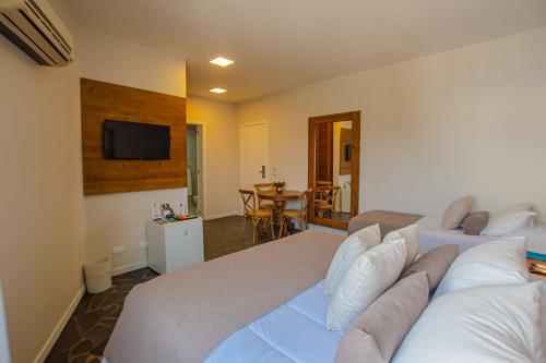 a bedroom with a large white bed and a television at Hotel Villareal São Francisco do Sul in São Francisco do Sul