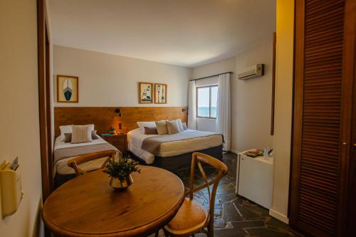 a hotel room with two beds and a table at Hotel Villareal São Francisco do Sul in São Francisco do Sul