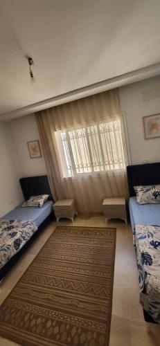 a bedroom with two twin beds and a rug at Maison indépendante in Hammamet Nord