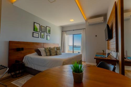 a bedroom with a bed and a table and a television at Hotel Villareal São Francisco do Sul in São Francisco do Sul