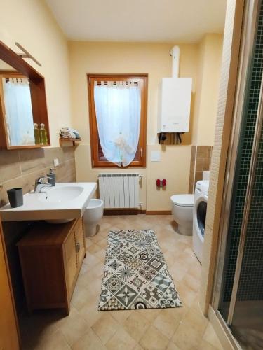 a bathroom with a sink and a toilet and a window at Appartamento Acero Rosso in Borno