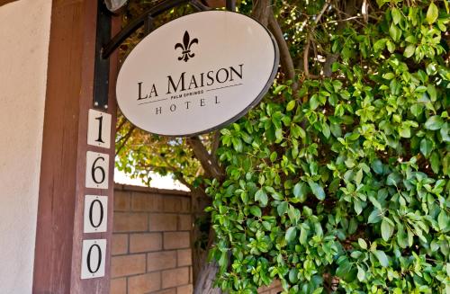 a sign for a la maison hotel on a bush at La Maison Hotel - Adults Only in Palm Springs