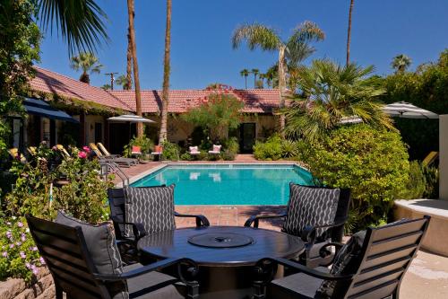 a patio with a table and chairs next to a pool at La Maison Hotel - Adults Only in Palm Springs