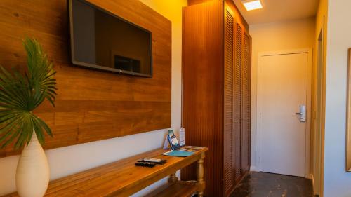a room with a television on a wall with a table at Hotel Villareal São Francisco do Sul in São Francisco do Sul