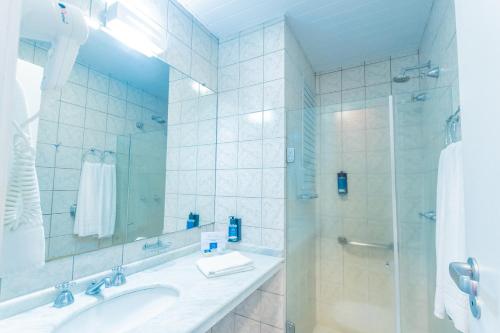 a white bathroom with a sink and a shower at Hotel Villareal São Francisco do Sul in São Francisco do Sul
