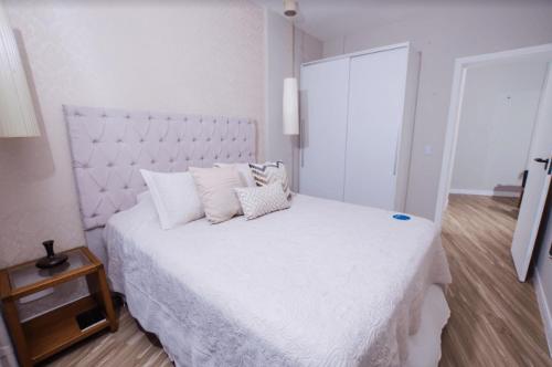 a white bedroom with a large white bed with pillows at Hotel Villareal São Francisco do Sul in São Francisco do Sul