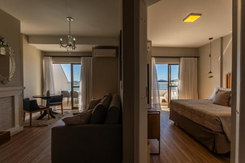 a bedroom with a bed and a couch and a living room at Hotel Villareal São Francisco do Sul in São Francisco do Sul