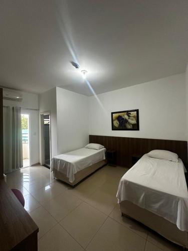 a bedroom with two beds and a light on the ceiling at Hotel Catarinense in Sorriso