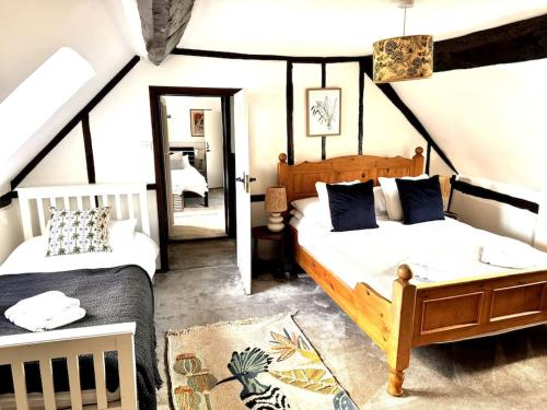 une chambre avec deux lits et un miroir dans l'établissement Stylish Tudor Cottage & Hot Tub, à Coombe Hill