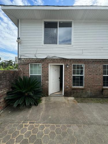 a brick house with a white door and a driveway at Cozy 2-Bedroom in Harvey