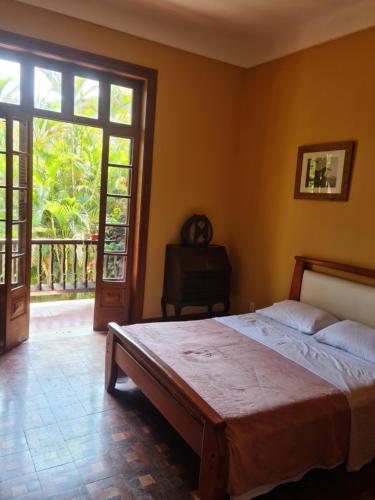 a bedroom with a bed and a large window at Carangola Guesthouse in Petrópolis