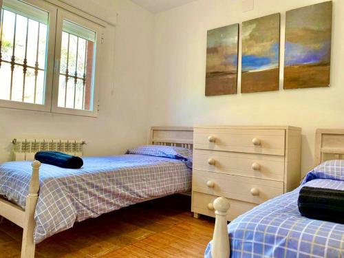 a bedroom with two beds and a dresser and two windows at Olival 2 in Las Herreras