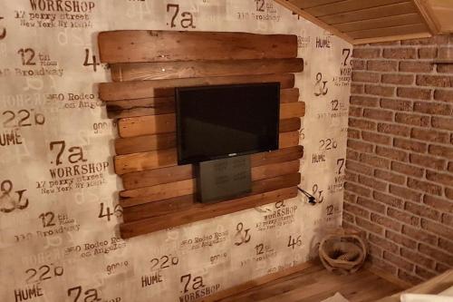 a tv on a wall with a wall made out of logs at Duvaro Guesthouse in Raduil