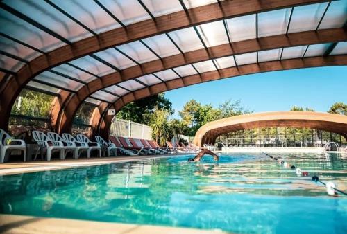 une personne se baignant dans une piscine sous un pont dans l'établissement Bungalow les Embruns, à Lège-Cap-Ferret