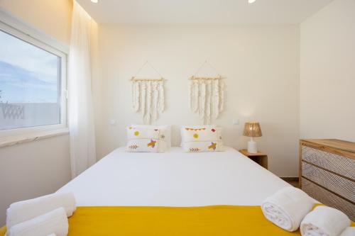 a white bedroom with a large bed and a window at Pontalaia Atlantic View in Sagres