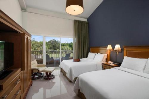 a hotel room with two beds and a television at Hodelpa Garden Suites - All Inclusive in Juan Dolio