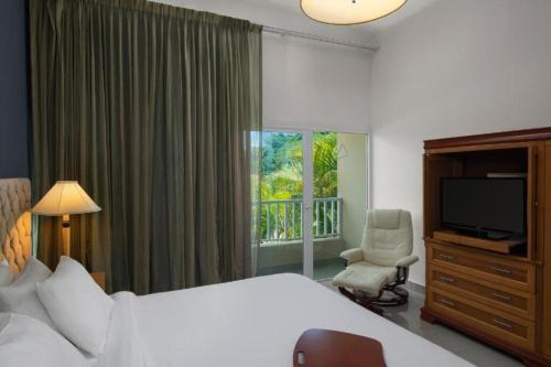 a bedroom with a bed and a television and a chair at Hodelpa Garden Suites - All Inclusive in Juan Dolio