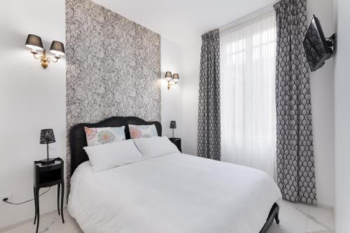 une chambre blanche avec un lit blanc et une fenêtre dans l'établissement Les Montgolfières, 2 Pièces, Porte de Versailles, à Paris