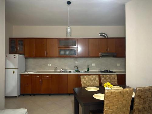 a kitchen with wooden cabinets and a table and a refrigerator at Turdiu center apart in Tirana
