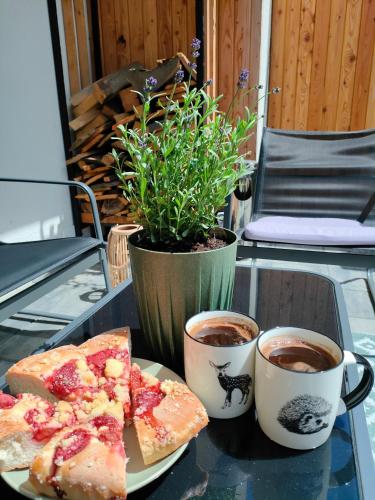 a table with a plate of pizza and two cups of coffee at Dom nad jeziorem WIDOKówka in Żywiec