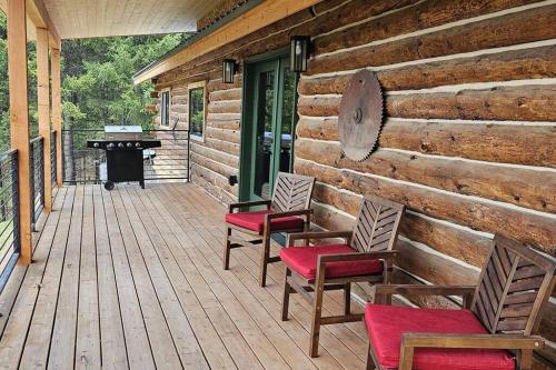 a porch with chairs and a piano on a log cabin at Cabin on 15 acres with Mtn view, firepit, Starlink in Whitefish
