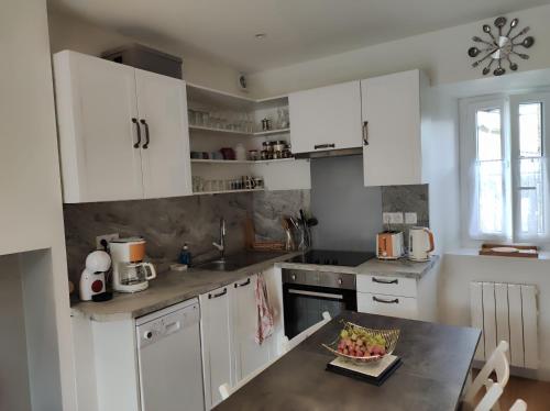 - une cuisine avec des placards blancs et un bol de fruits sur une table dans l'établissement Charmante maison de montagne, à Cierp