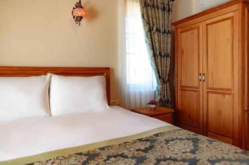 a bedroom with a bed with white sheets and a window at Cappadocia Villa Comfort in Nevsehir