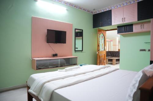 a bedroom with a large bed and a flat screen tv at The HR STAY INN TIRUPATI - LUXURY HOMESTAY - NEAR ALIPIRI BUS STAND AND KAPILATEERTHAM - 24 HRS HOT WATER-150 MBPS SPEED FREE WIFI & ALL OTT APPS in Tirupati