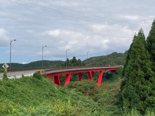a red bridge in the middle of a road at やまおう　宿＆カフェ in Nikaho