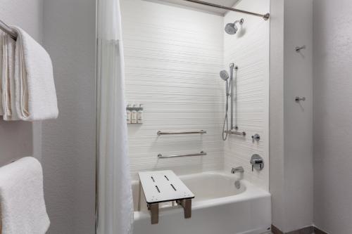 a white bathroom with a tub and a table in it at avid hotel North Platte by IHG in North Platte