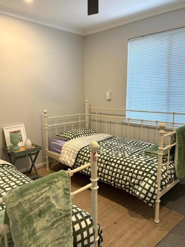 a bedroom with two beds and a chair and a window at Versatile summer beach house or cosy winter retreat! in Mandurah