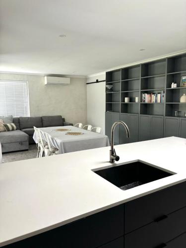 a kitchen with a sink and a living room at Versatile summer beach house or cosy winter retreat! in Mandurah
