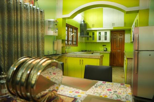 a yellow kitchen with a table and a refrigerator at The HR STAY INN TIRUPATI - LUXURY HOMESTAY - NEAR ALIPIRI BUS STAND AND KAPILATEERTHAM - 24 HRS HOT WATER-150 MBPS SPEED FREE WIFI & ALL OTT APPS in Tirupati